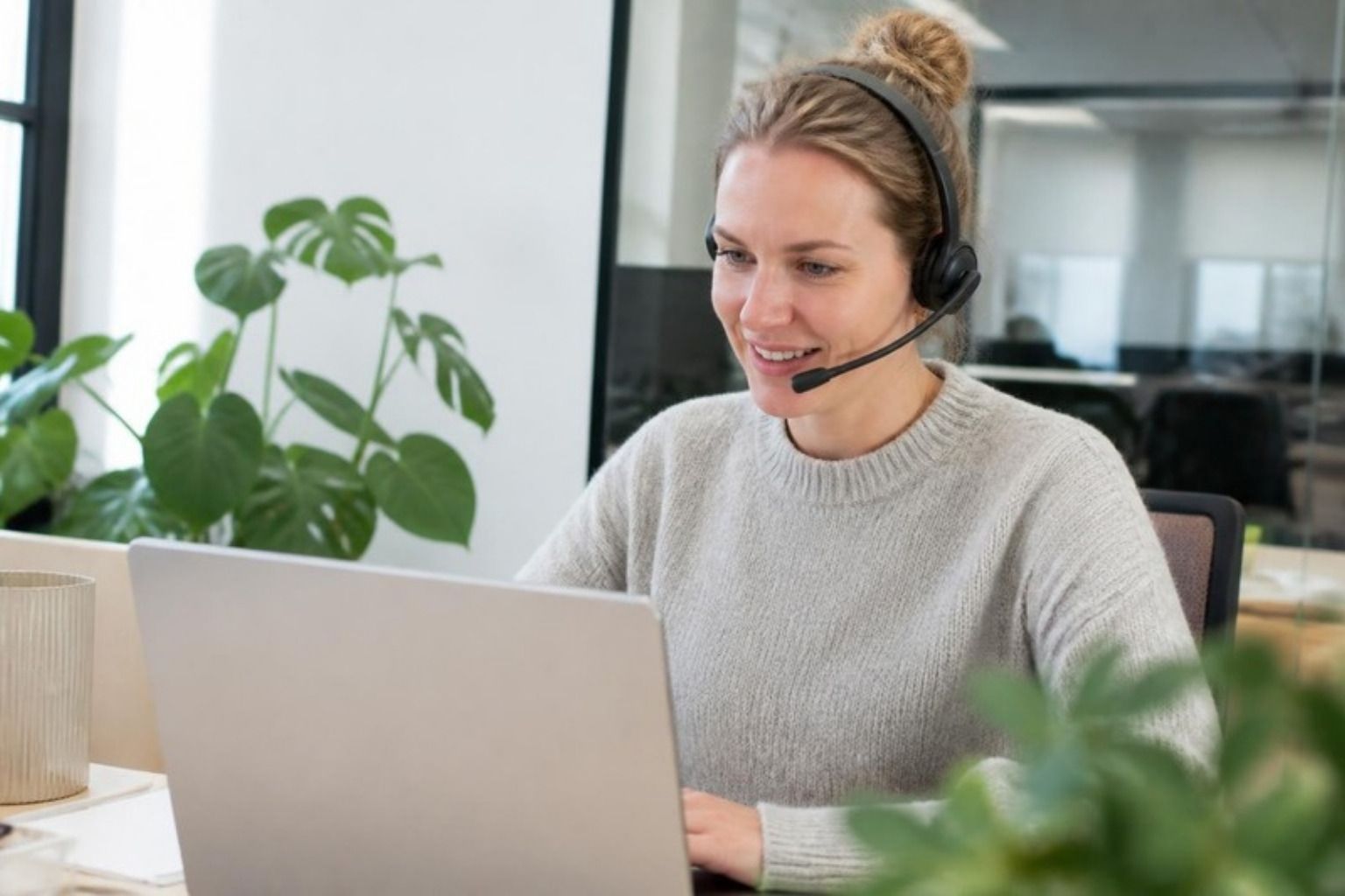 Smilende kunderådgiver med headset ved computer