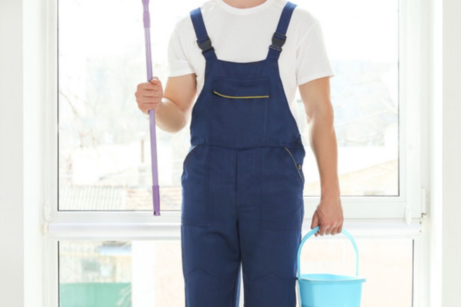 Vinduespudser i blå overalls med spand og vinduesvasker på skaft